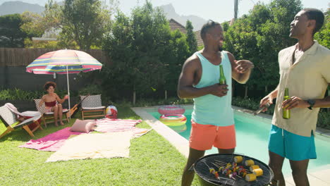 diverse friends enjoying barbecue by pool, dancing and laughing on sunny day