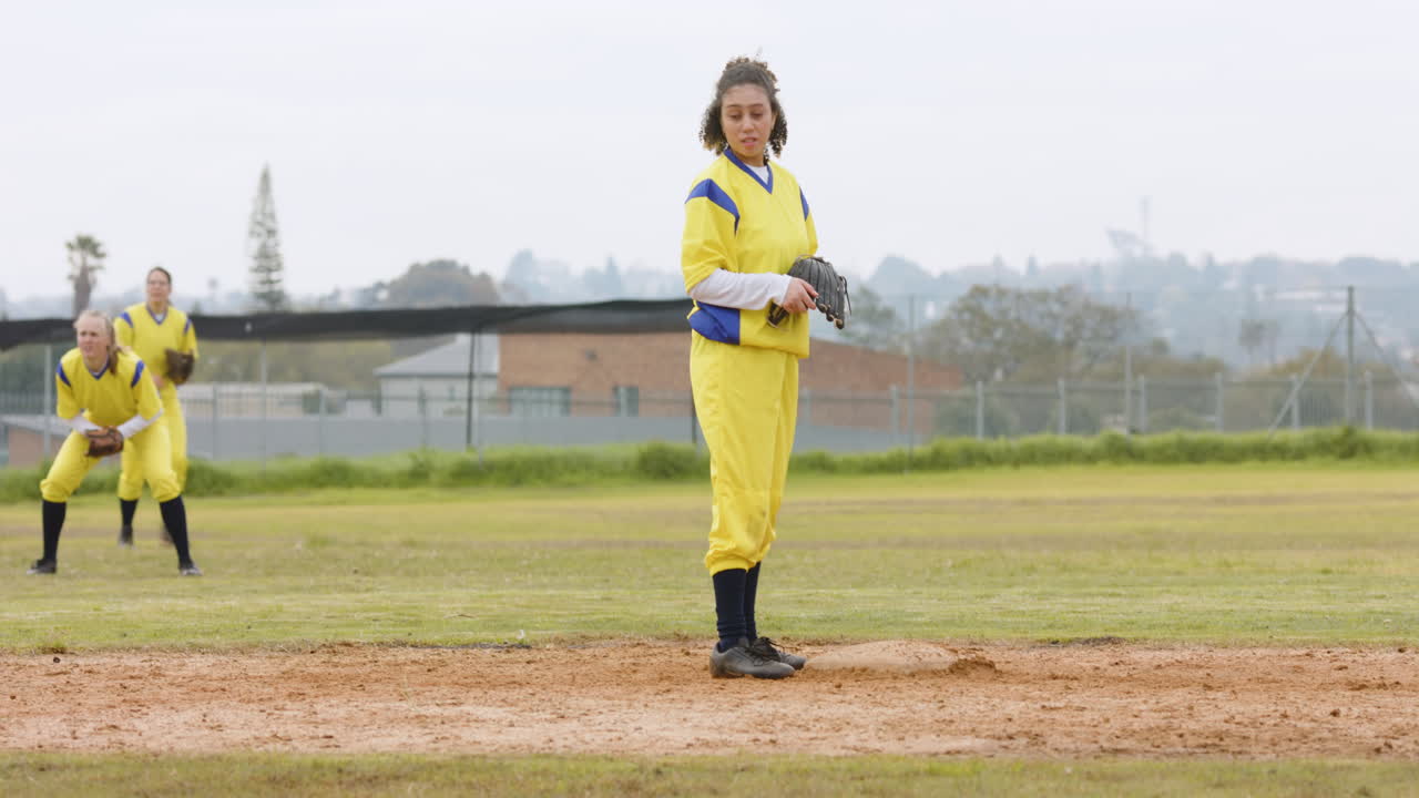 Multiracial female baseball players playing baseball, catching and throwing the ball on a pitch