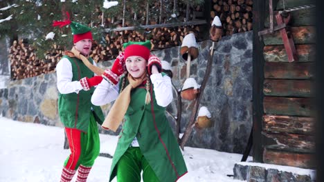 joyful elves playing in the snow near the house. fairy heroes elves a boy and a girl having snowball fight on winter holidays