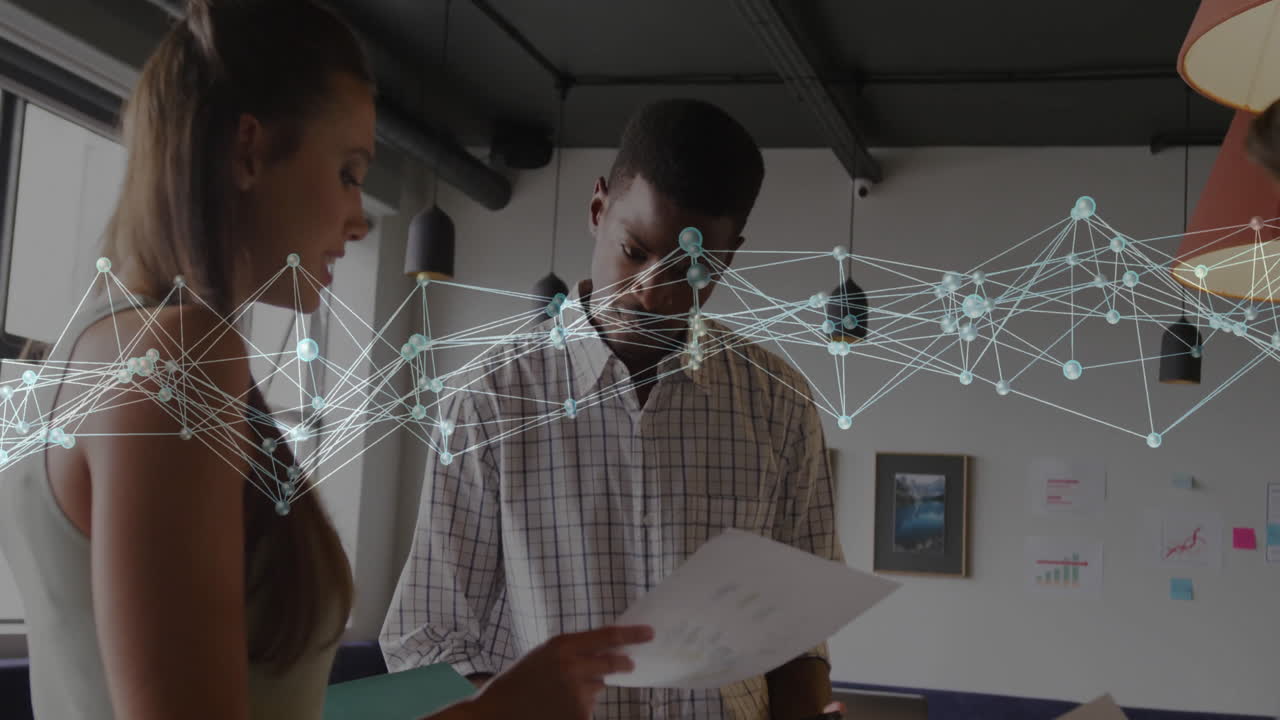 Three coworkers reviewing printed documents in business office, with digital network graph overlay