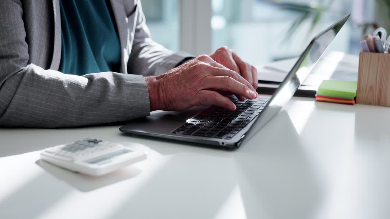Professional Working on Laptop and Calculator in Bright Office