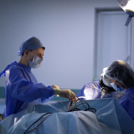 team of neurosurgeons having operation on a patient. three doctors wearing special uniform and equipment helping the patient in the surgery