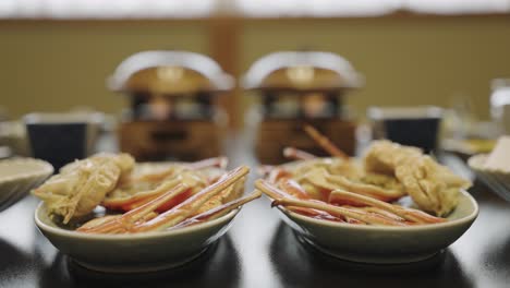 Cangrejo-De-Nieve-Japonés-En-Platos,-Con-Nabe-Ollas-Calientes-En-Segundo-Plano.