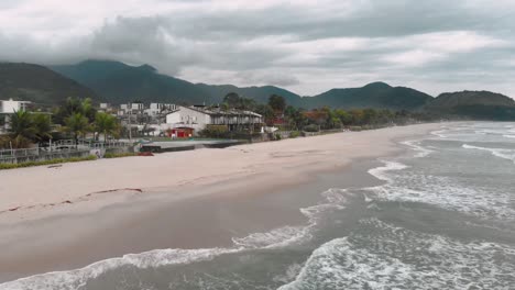 Drone-footage-of-the-beach-above-the-sea,-mountain-in-front-of-the-sea,-cloudy-day,-waves,-landscape-of-Juquehy,-Ubatuba,-northern-coast-of-São-Paulo,-Brazil