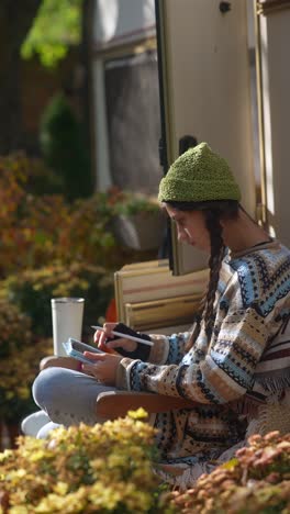 young woman sketching outdoors in a camping chair