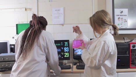 dos mujeres científicas están trabajando con líquidos y computadoras en un laboratorio