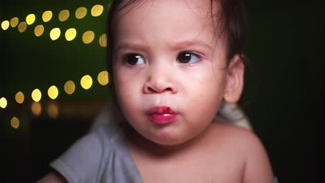 Baby-boy-RACK-FOCUS-PULL-eating-fruit-with-golden-Bokeh-in-dark-room-happy-and-smiling