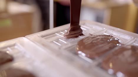 chocolatier de cultivos vertiendo chocolate derretido en forma en la cocina