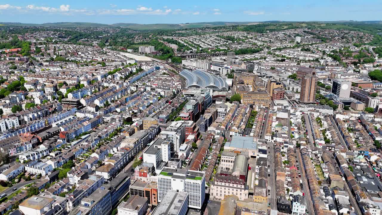 Aerial drone view of Brighton’s iconic railway station and stunning south downs in the background. The city’s vibrant energy captured from above in high summer.