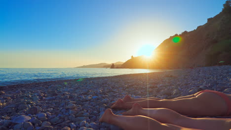 Sunset-at-Playa-de-las-Alberquillas,-Andalusia,-Spain,-with-a-clear-blue-sky-on-the-background-and-a-couple-of-female-relaxing-on-the-foreground