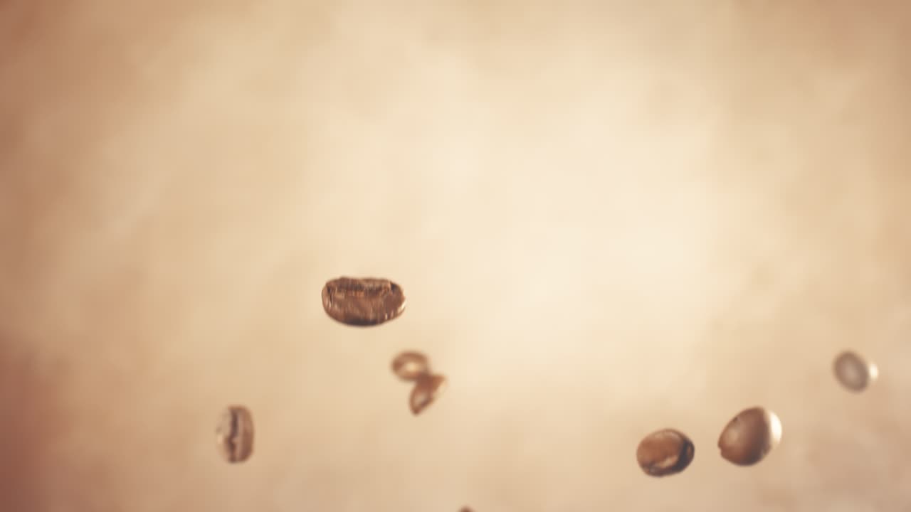 Fragranza di chicchi di caffè che fluttuano nell'inquadratura. Chicchi di caffè ripresi con una fotocamera super slow motion a 1000 fps.