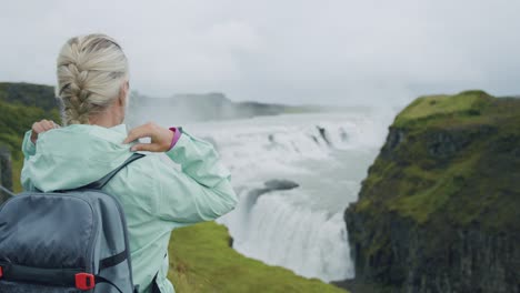 mujer viajera con mochila frente a la hermosa cascada de gullfoss, famosa atracción turística y destino histórico de islandia en el círculo dorado