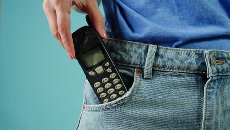 mujer con un viejo teléfono en el bolsillo de sus vaqueros