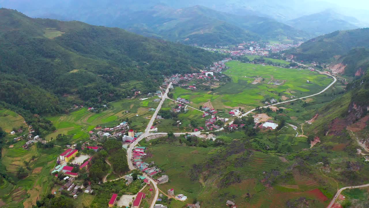 inclinación aérea lenta de una comunidad agrícola vietnamita asentada en las montañas brumosas