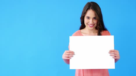 hermosa mujer sosteniendo un cartel en blanco sobre un fondo azul