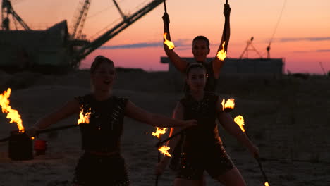 Frauen-Mit-Feuer-Bei-Sonnenuntergang-Auf-Dem-Sand-Tanzen-Und-Zeigen-Tricks-Vor-Dem-Wunderschönen-Himmel-In-Zeitlupe