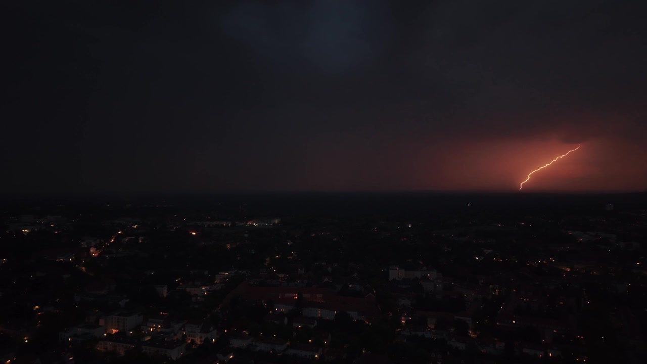 Lampo che illumina nuvole temporalesche scure sopra le luci della città di Berlino, mostrando fenomeni meteorologici drammatici e la potenza della natura. Splendida vista aerea con panorama inverso ripreso da drone.