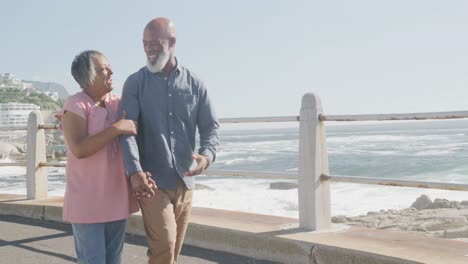 feliz pareja afroamericana mayor caminando por el paseo marítimo junto al mar, cámara lenta