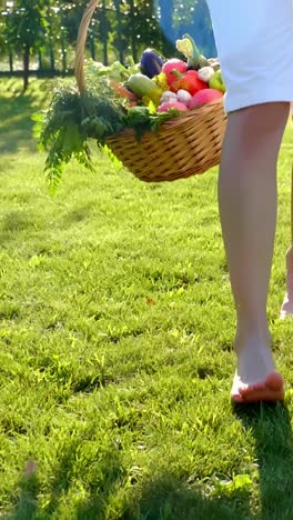 woman carrying a basket of vegetables in a garden