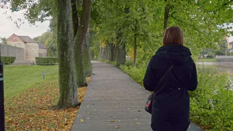 Una-Chica-Camina-Sobre-Un-Puente-Peatonal-De-Madera-En-El-Parque.