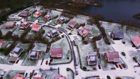 luxury houses in winter landscape with snow next to river top down aerial