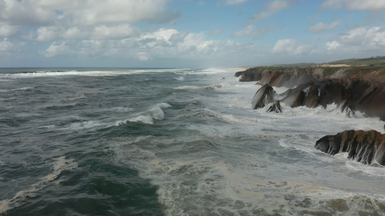 antena baja de grandes olas rompiendo en acantilados rocosos