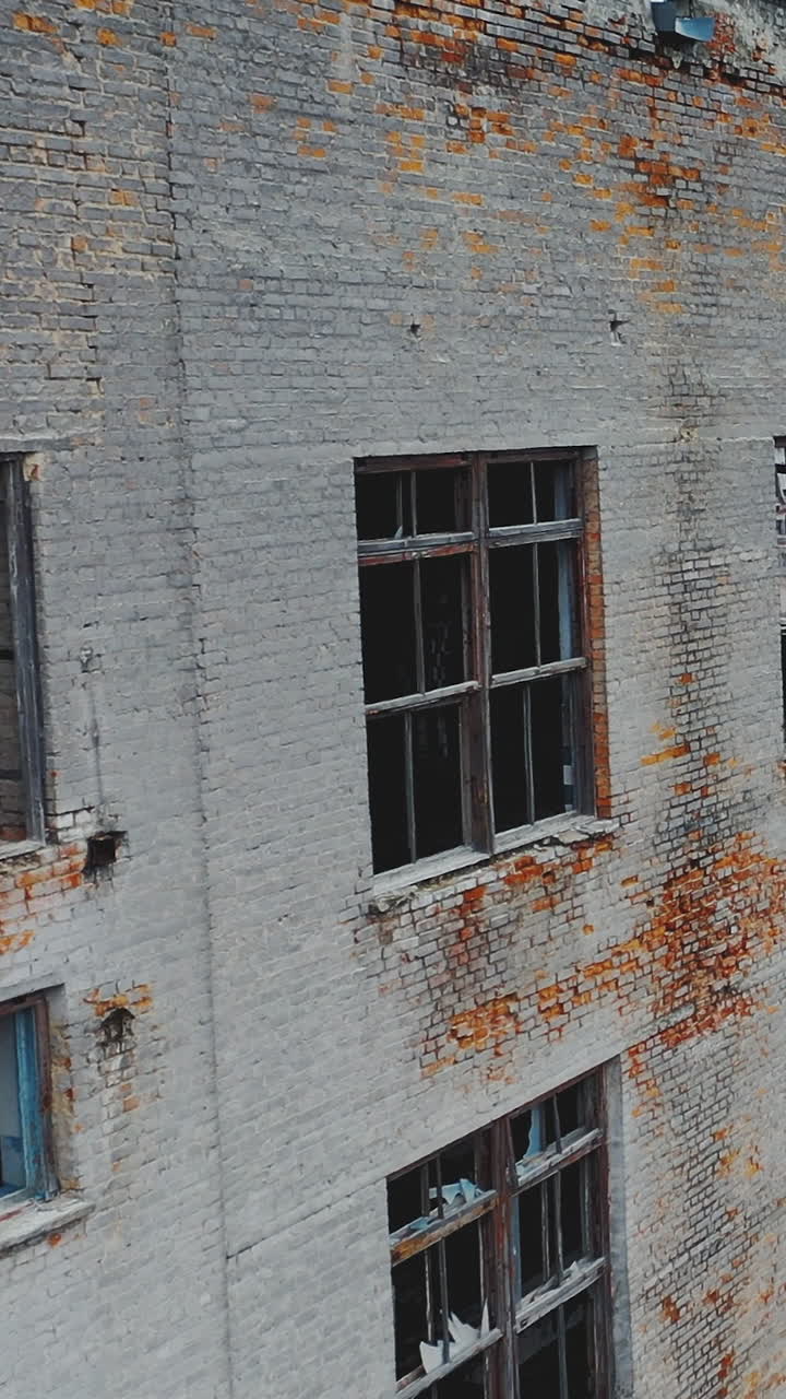 Ruined old brick buildings with broken windows and doors. Industrial park. Aerial view. Vertical video