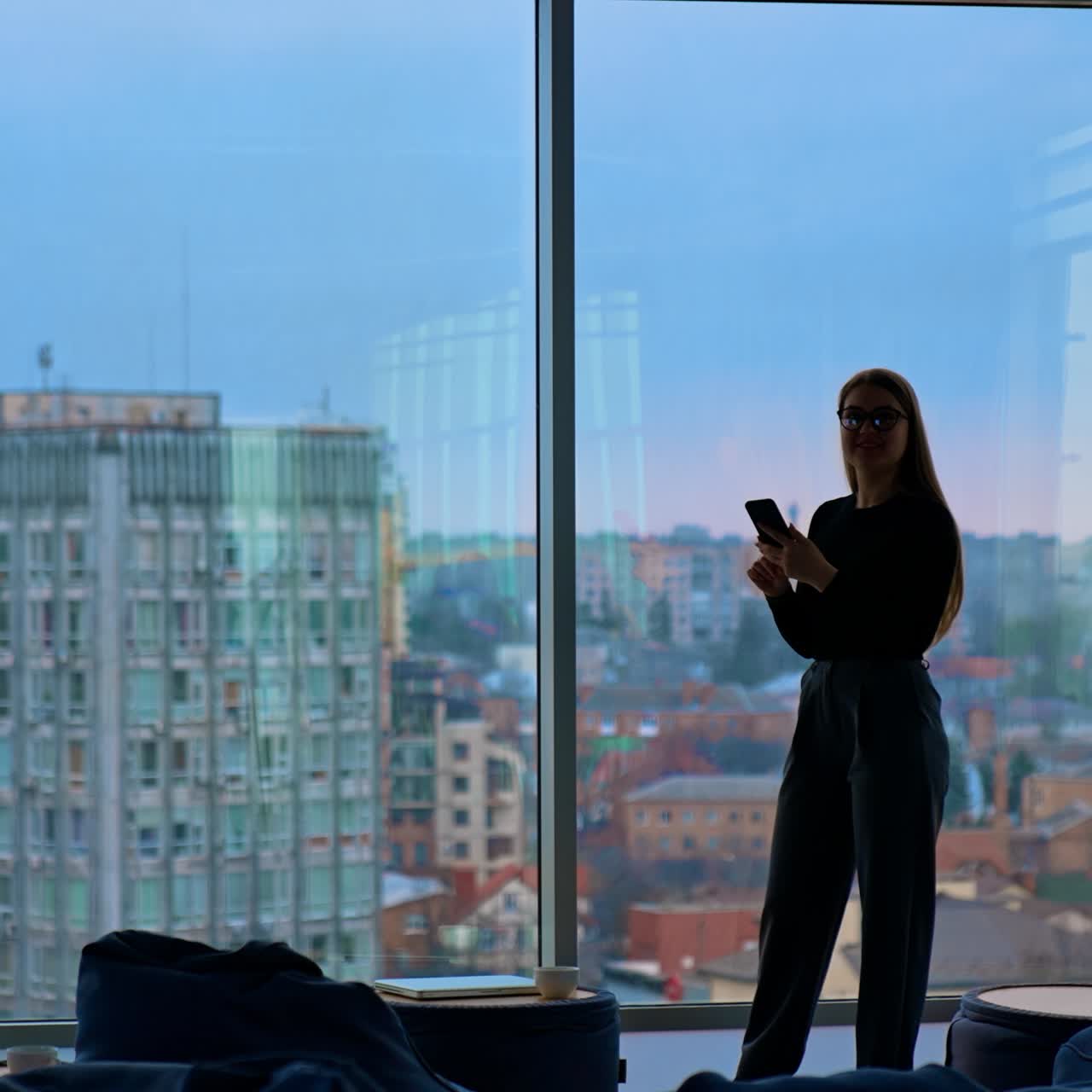 A beautiful smiling woman wearing eyeglasses is using a phone