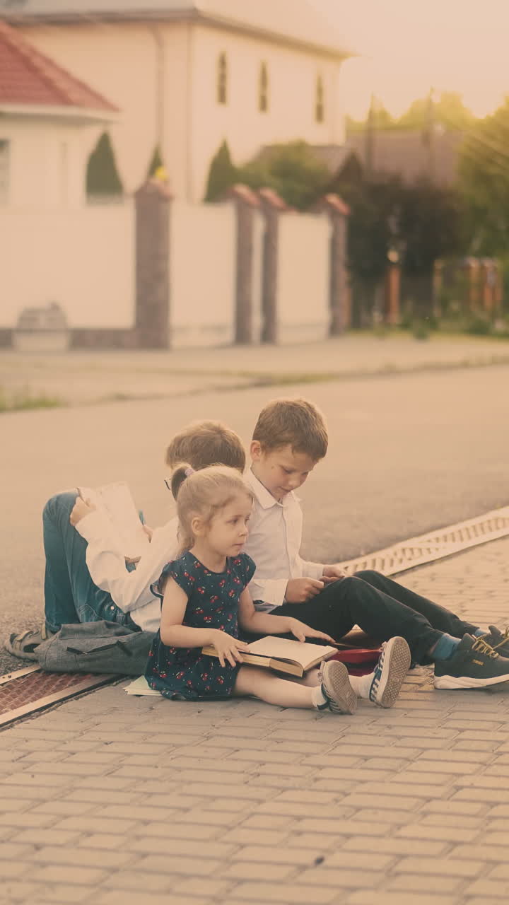 schoolboy in white shirt sits on pavement and throws away book young sister gives new textbook on sunny day