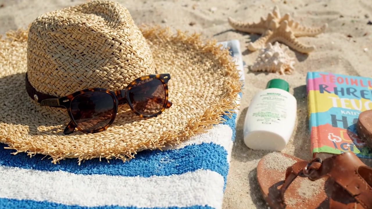 A Relaxing Day at the Beach Featuring Sun Hat, Sunglasses, Sunscreen, and Footwear on Sandy Shore with Colorful Beach Towels and Decorative Shells