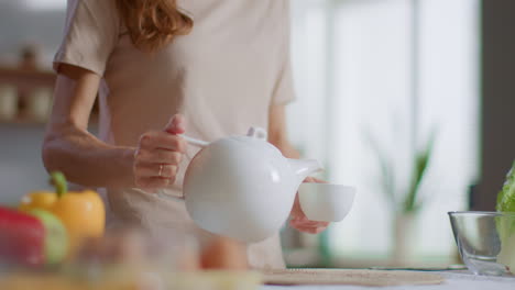 Frau-Gießt-Tee-In-Eine-Teetasse