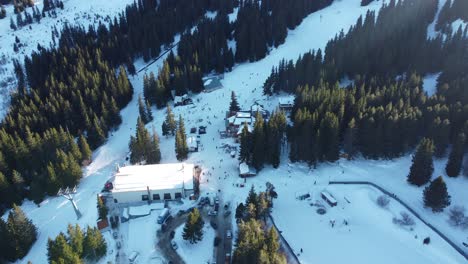 overhead aerial clip of a busy mountain ski resort with skiers and snowboarders on a slope and a cable car station near sofia, bulgaria