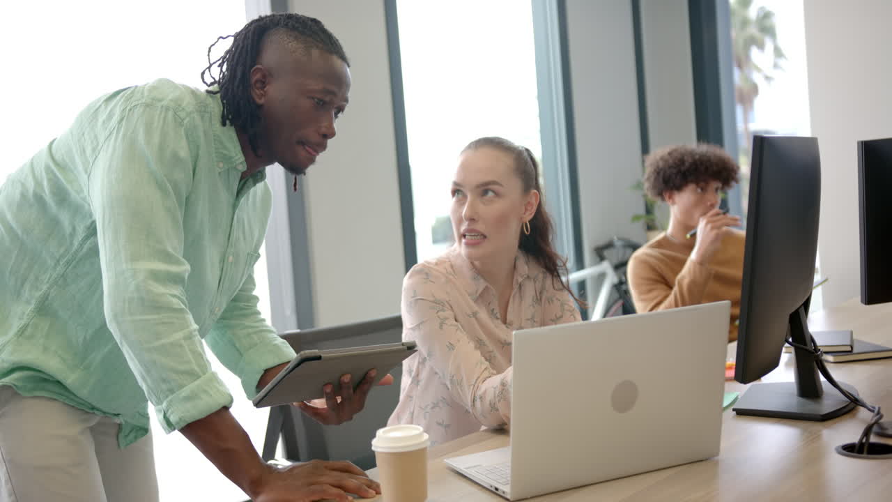Collaborating in office, colleagues discussing project using laptop and tablet