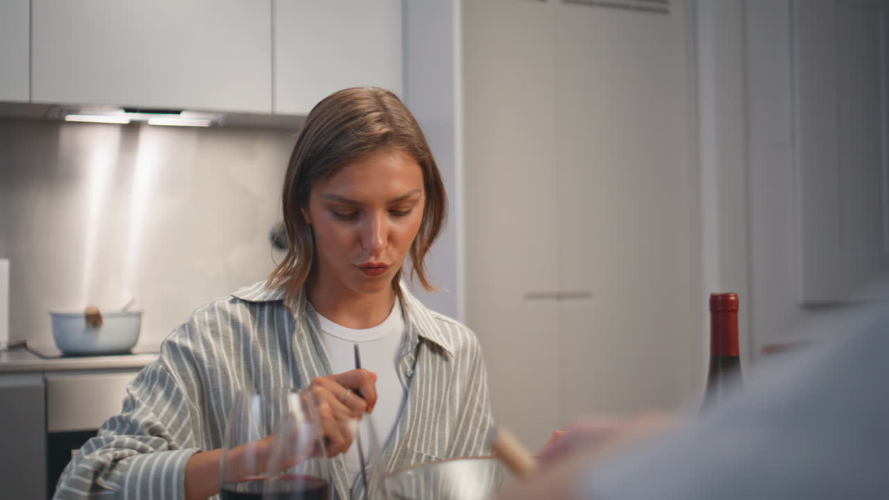 Joyful woman dining home with romantic partner. Smiling wife enjoying pasta meal