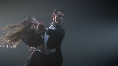 ballroom dance couple twirling in dark space. elegant man and woman dancing.