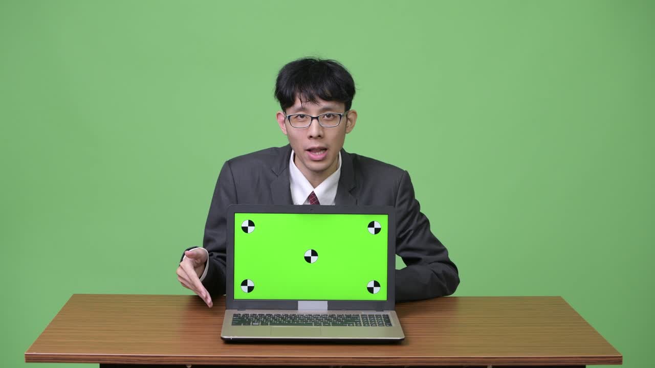 젊은 아시아 사업가 가 카메라 에 노트북 을 보여주면서 이야기 하고 있다