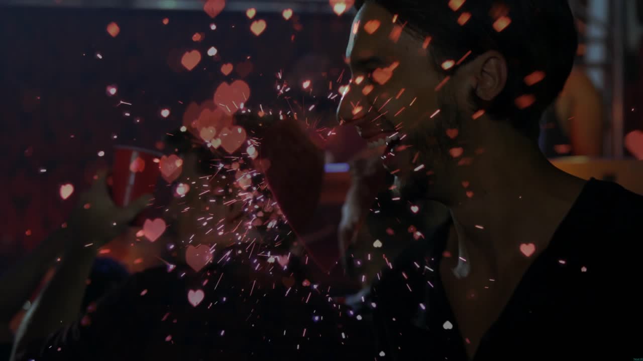 Hand pressing heart popper at entertainment party, sending confetti and sparkles celebrating moment