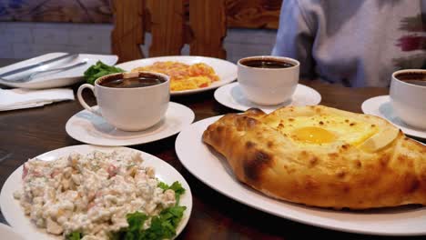 adjarian khachapuri en una mesa en un restaurante georgiano junto a ensalada, tortilla y café
