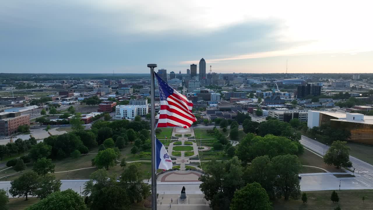 bandera estadounidense y bandera del estado de iowa ondeando frente a la ciudad capital, des moines, ia