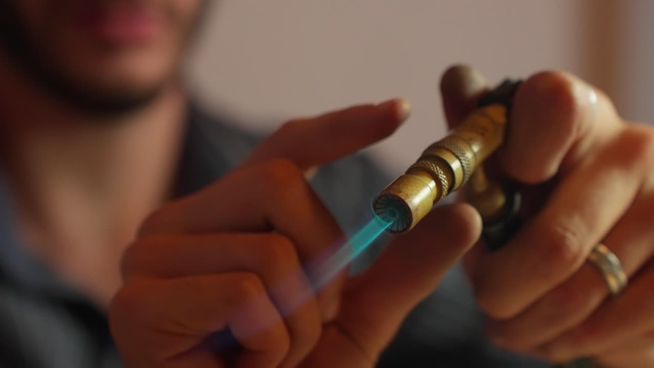 un artesano se centra mientras enciende un encendedor de butano, con precisión como una luz cálida ilumina el lugar de trabajo