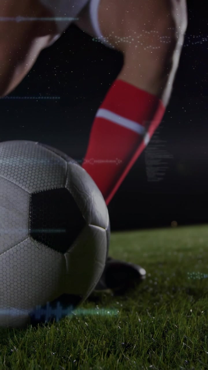 Dikey video: Erkek oyuncu ağırlığını aktarıyor, futbol topuna yaklaşıyor ve gece topa vurmaya hazırlanıyor.