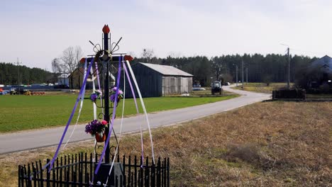 rural landscape with roadside shrine and farm buildings in the background on a clear day in early spring