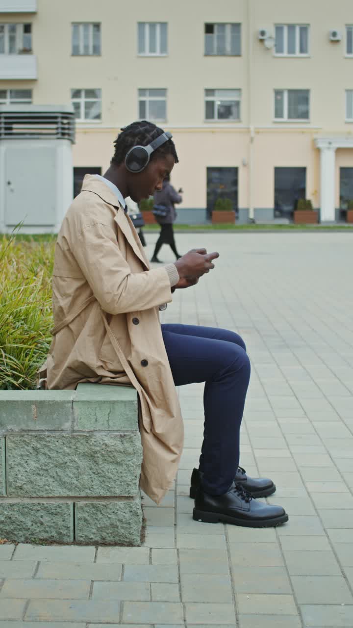 Uomo con le cuffie che usa il cellulare all'aperto