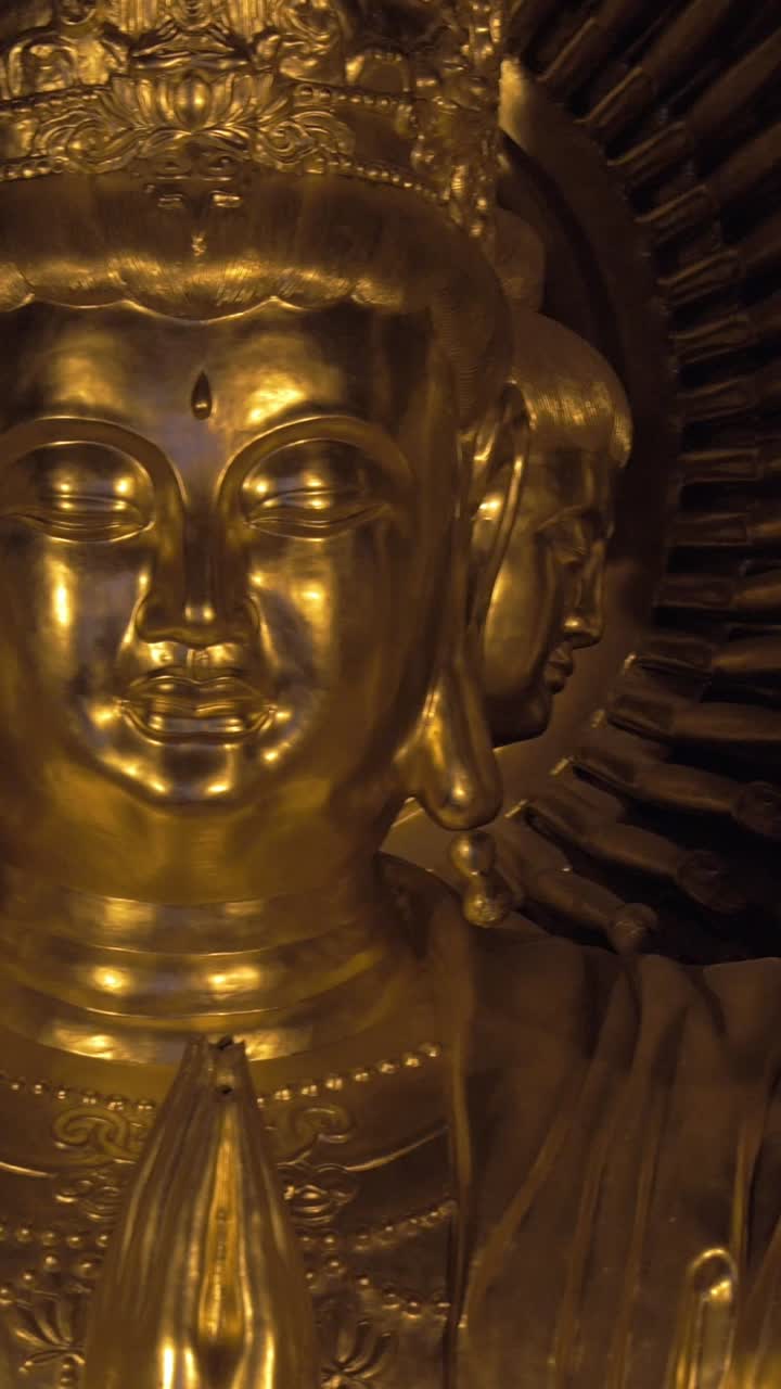 Statua dorata di Buddha ornata con più volti e mani