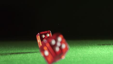 red dice falling and bouncing on green table on a dark background. shot on super slow motion camera 1000 fps