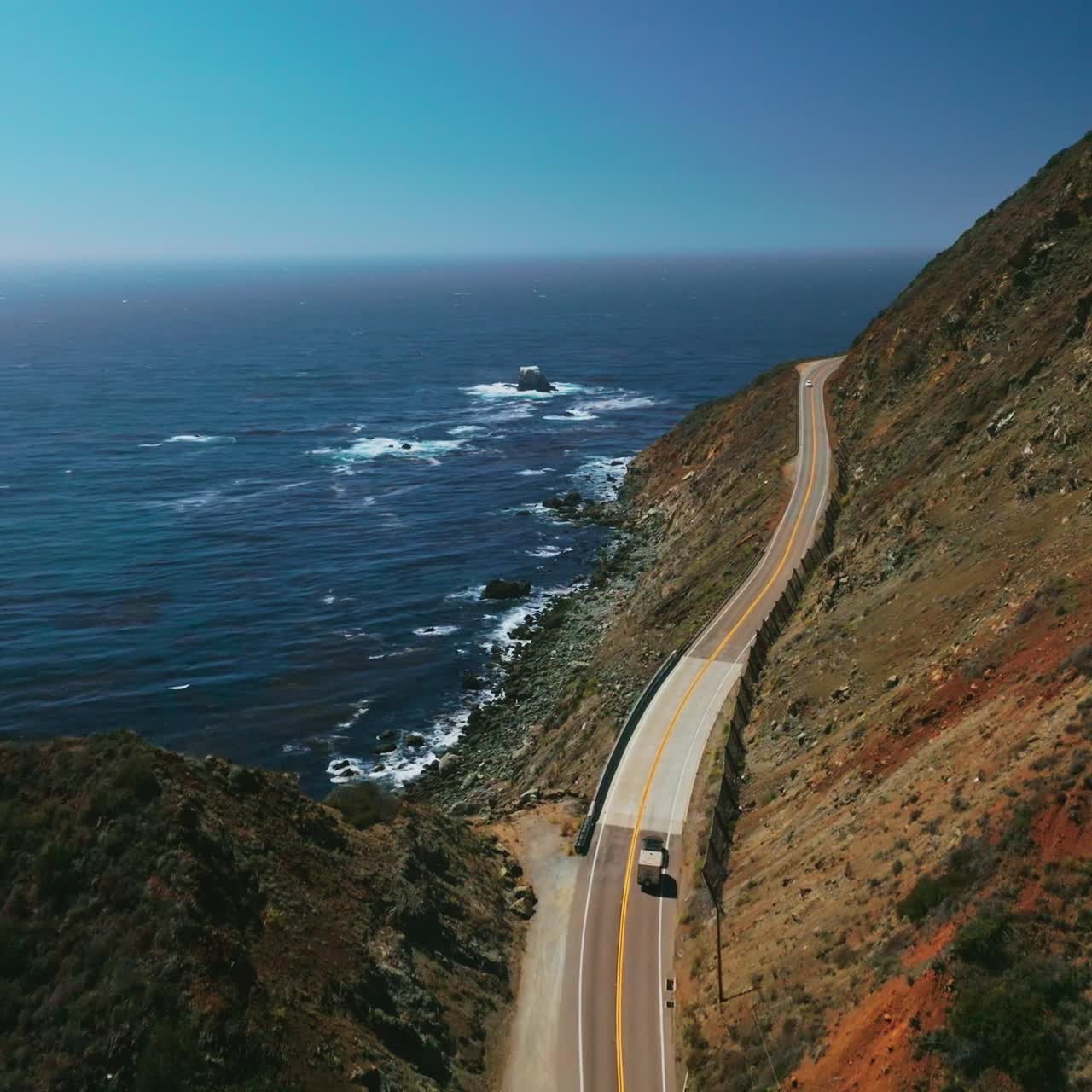 Following the truck riding by the dangerous mountainous highway of California on sunny day. Amazing blue ocean opening to the view