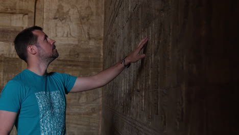 person exploring ancient carvings at dendera temple in egypt, observing the artwork