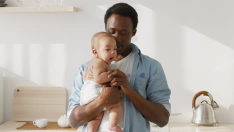 an african american father cuddling his baby at home