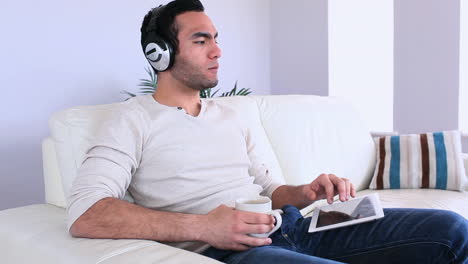 hombre guapo escuchando música relajándose en un sofá