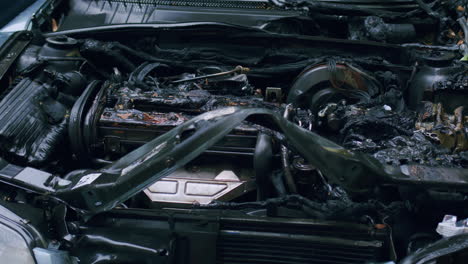 burnt car engine with charred and melted parts, severe fire damage